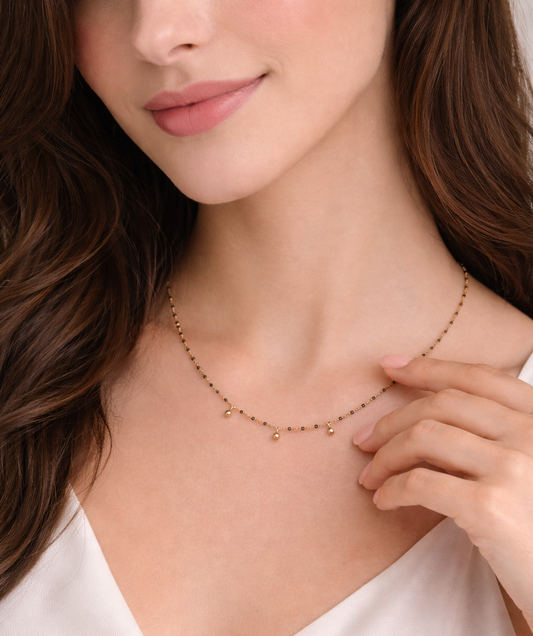 Modelo luciendo el collar Nocturne, una cadena fina de plata bañada en oro con detalles de piedras de ónix.