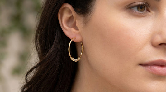 Modelo luciendo los aros Rivage de plata 925 bañada en oro 18K, mostrando cómo quedan puestos de perfil con un estilo minimalista.