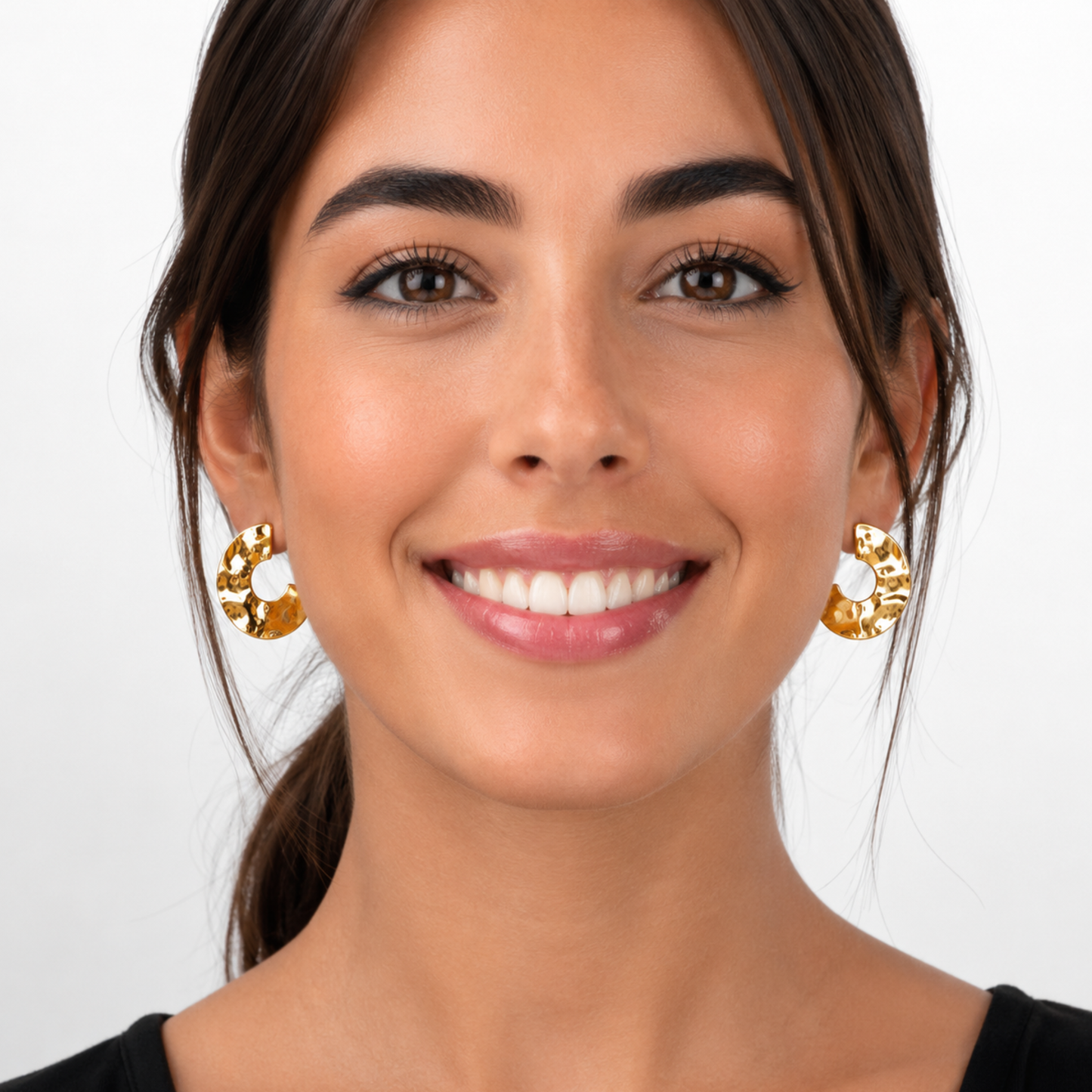 Modelo de frente con pendientes de aro abierto STRUTTURA con baño de oro 18K de textura martillada