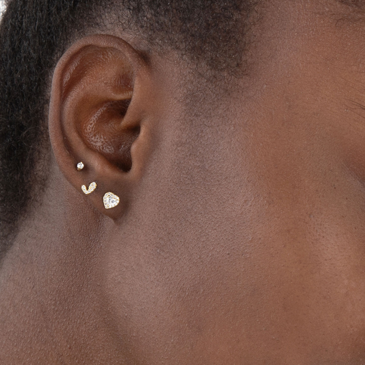 Modelo luciendo pendientes COEUR dorados de corazón con circonitas