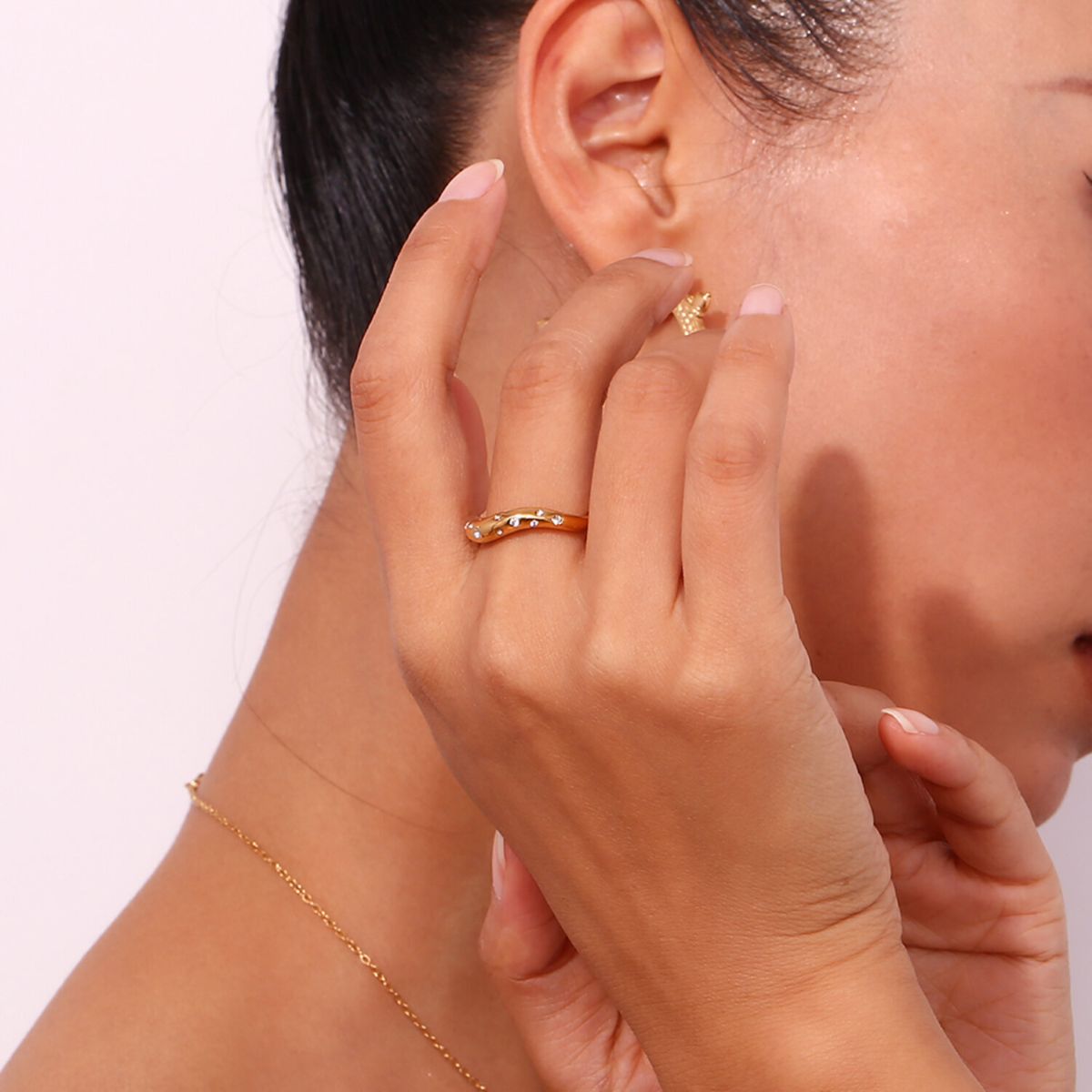 Primer plano de modelo con el anillo Aere de acero inoxidable y baño de oro 18k destacando su brillo y elegancia.