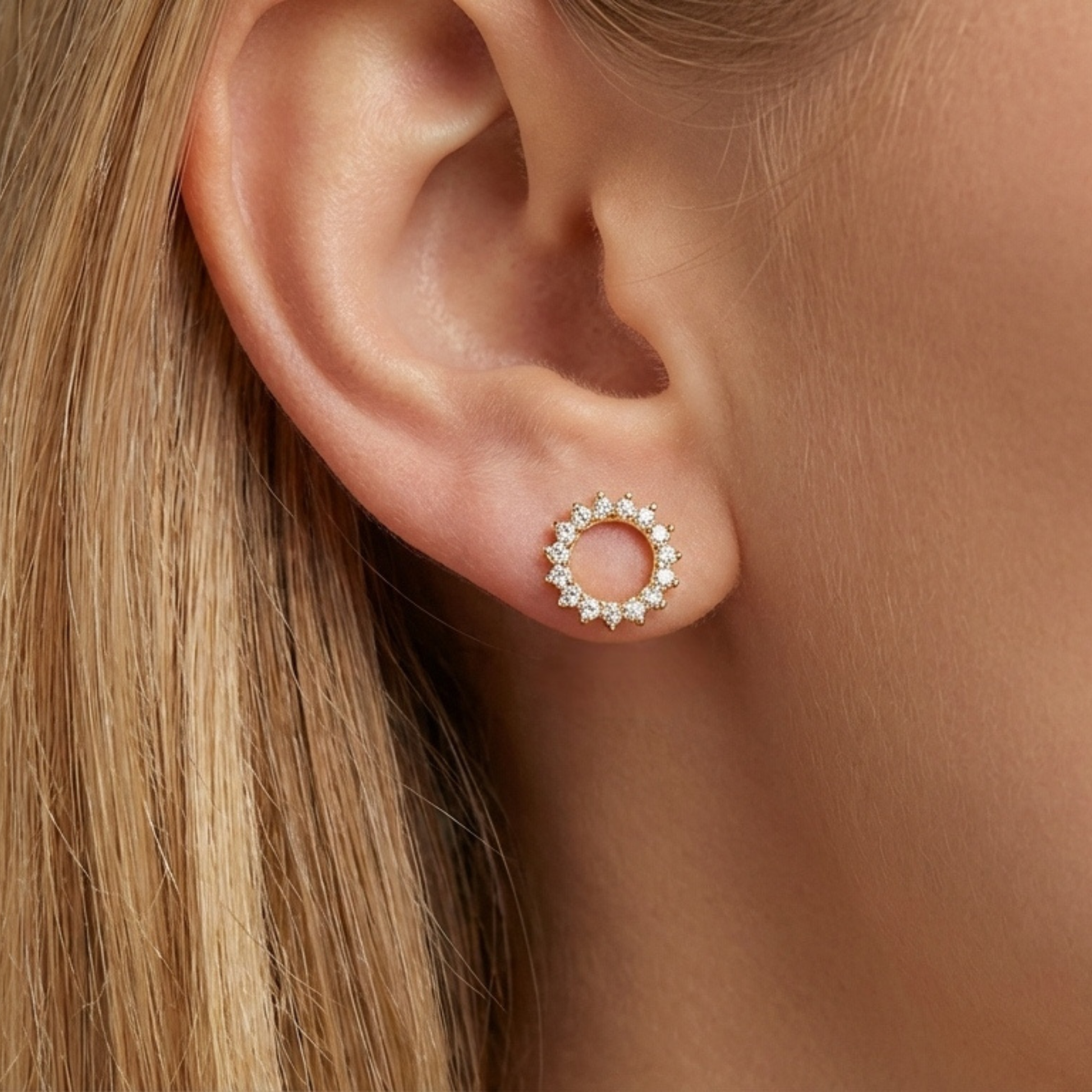 Modelo luciendo pendientes SOLSTICE dorados con diseño de sol en la oreja