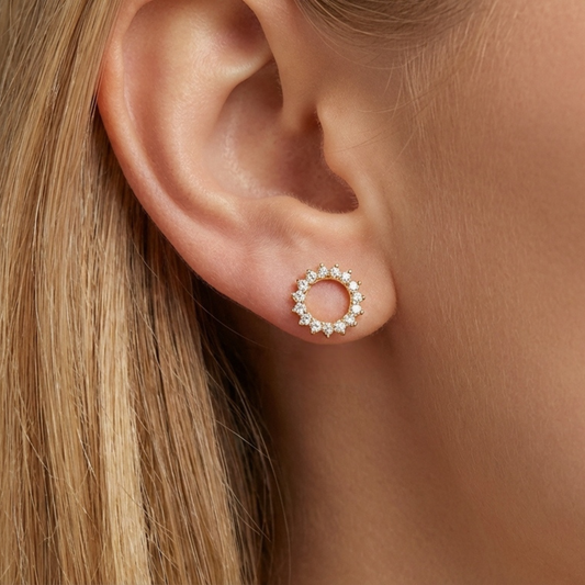 Modelo luciendo pendientes SOLSTICE dorados con diseño de sol en la oreja