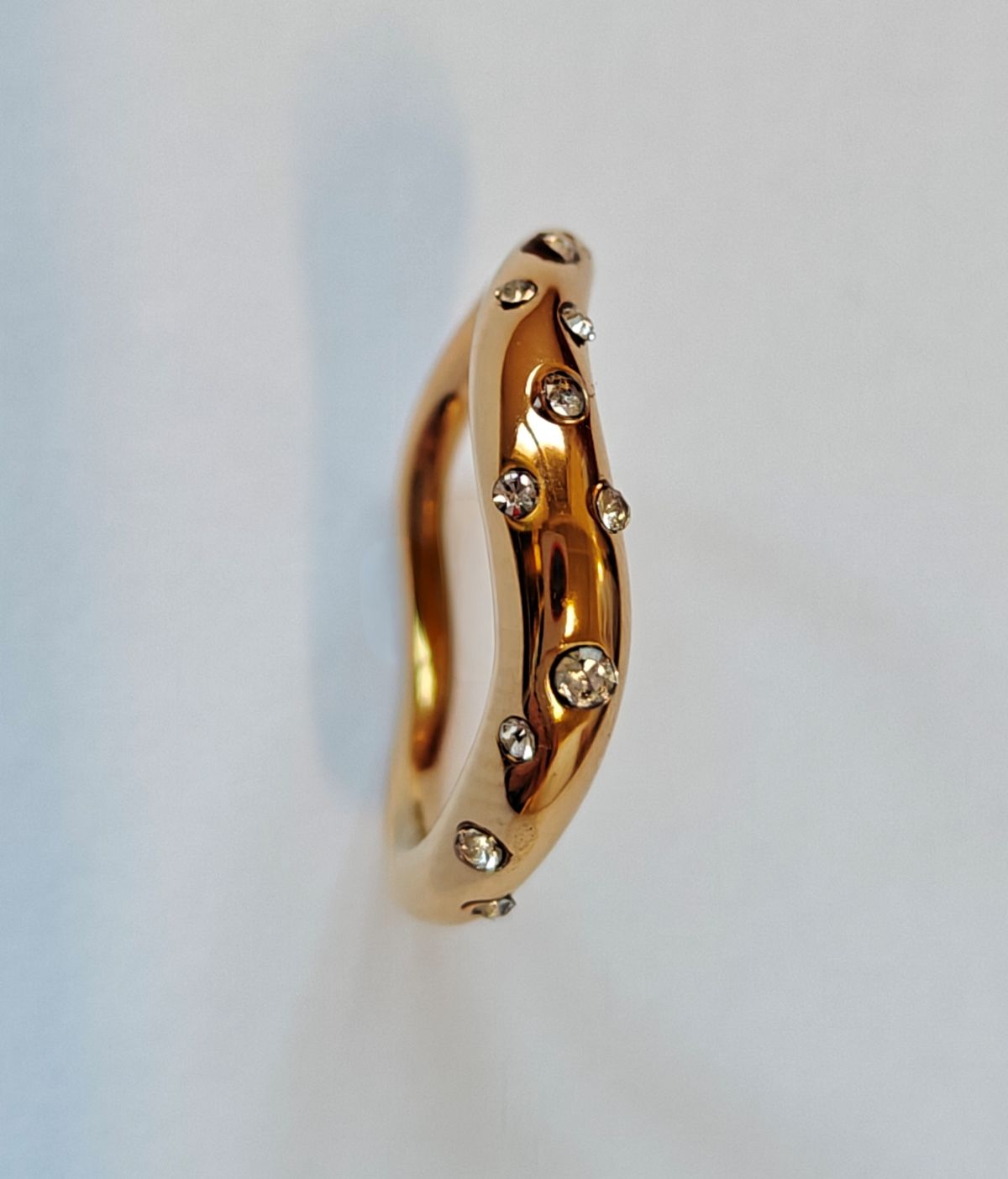 Vista de perfil del anillo Aere mostrando la forma ondulada y el acabado pulido del acero bañado en oro.