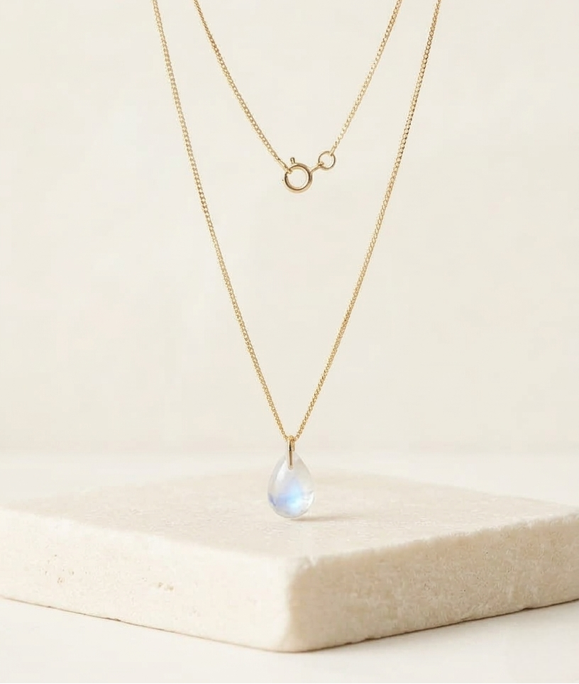 Primer plano de colgante Malbae de la línea Pure con diseño orgánico en plata de ley 925 bañada en oro de 18k y piedra luna de brillo irisado.