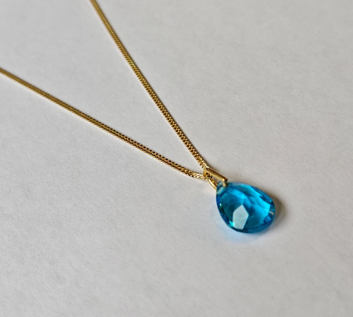 Collar de plata bañado en oro de 18 quilates con diseño sutil y colgante de topacio azul natural