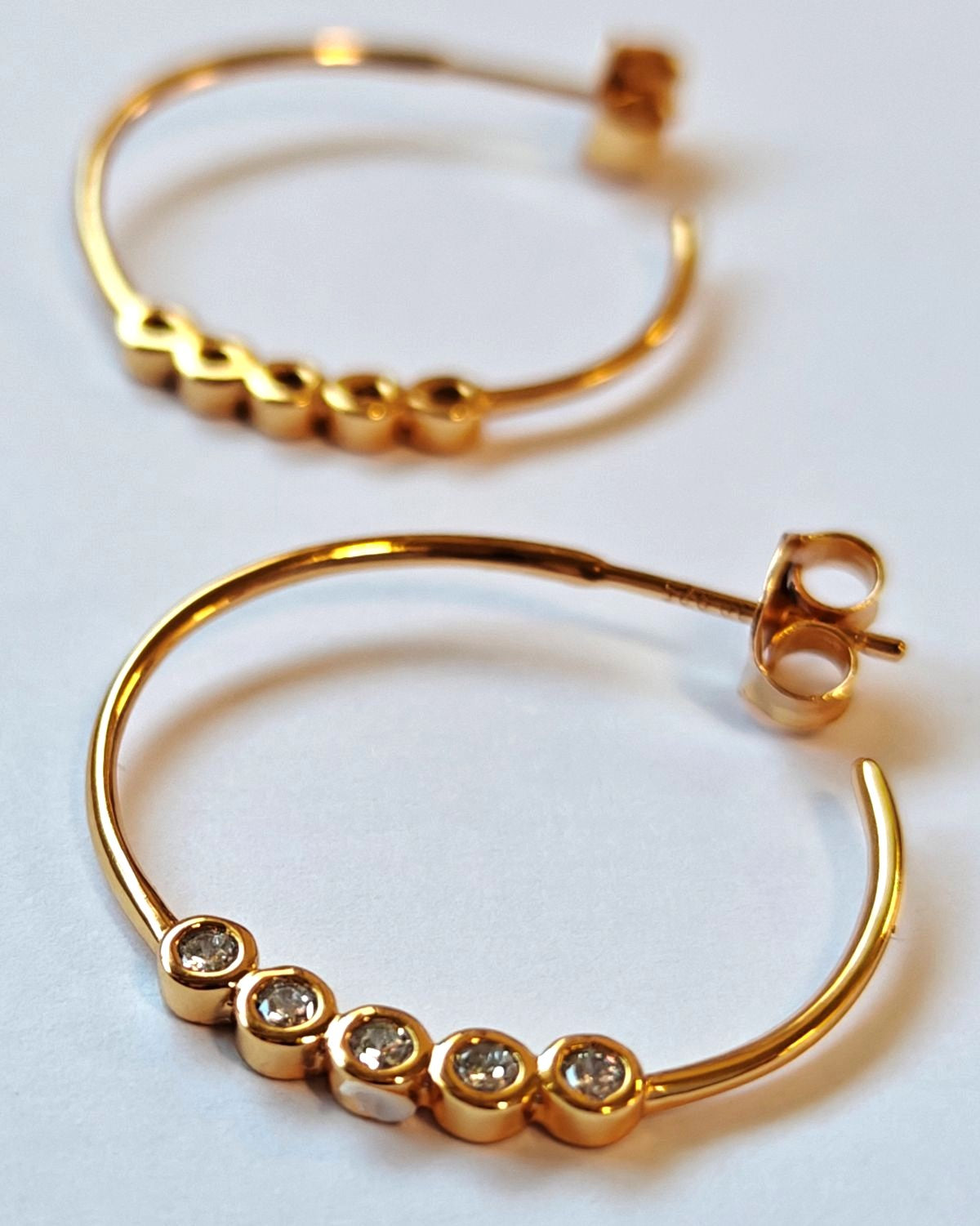 Detalle macro primer plano de las circonitas blancas engastadas en la base de los pendientes de aro Rivage plata 925 baño en oro 18K de MALBAE.