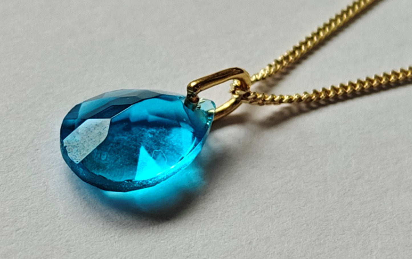 Primer plano del colgante con topacio azul natural en el collar de plata y oro 18k de Malbae