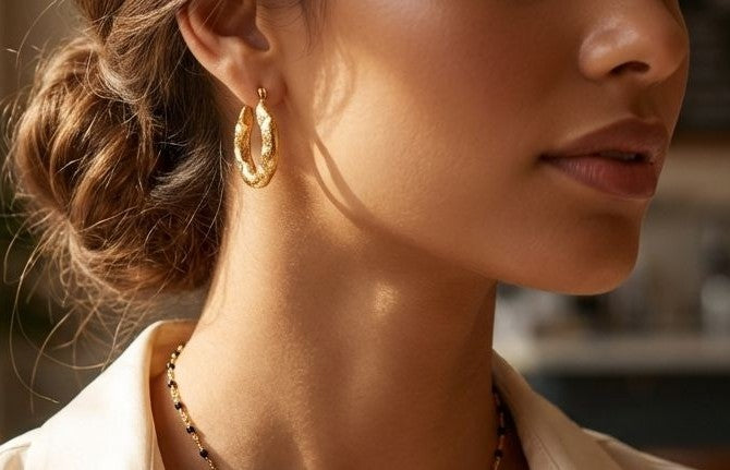 Detalle de pendientes de aro Roccia en acero inoxidable con baño de oro de 18k resistentes al agua de MALBAE puestos en modelo