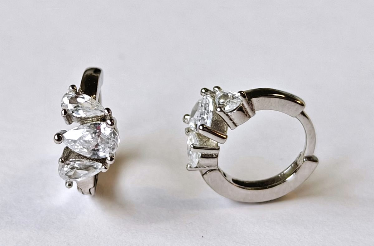 Detalle frontal y perfil de los pendientes de aro pequeños de plata de ley con engaste de circonitas de alta calidad.
