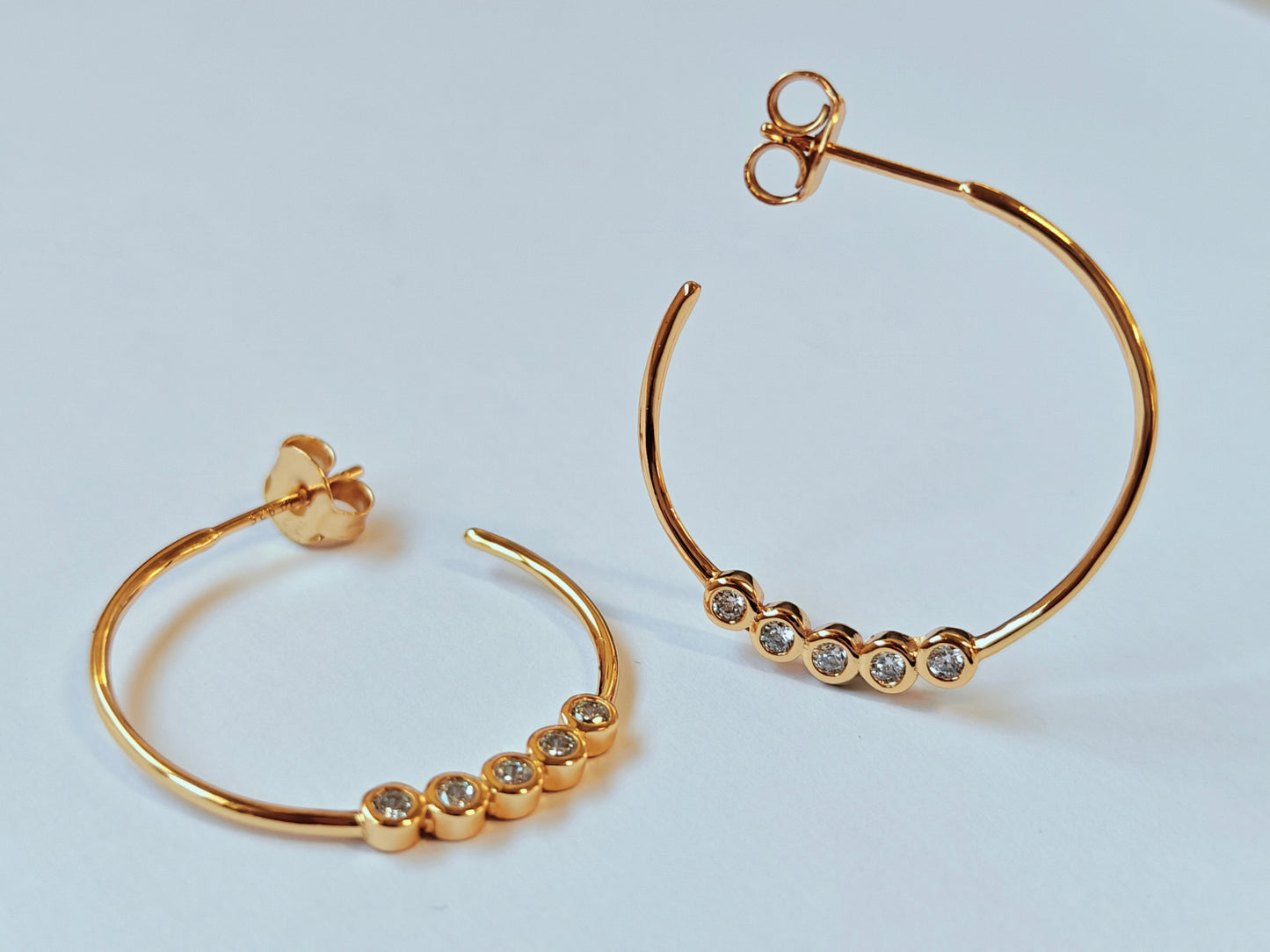 Pareja de pendientes de aro finos plata 925 bañado en oro 18k con circonitas Rivage sobre fondo neutro.