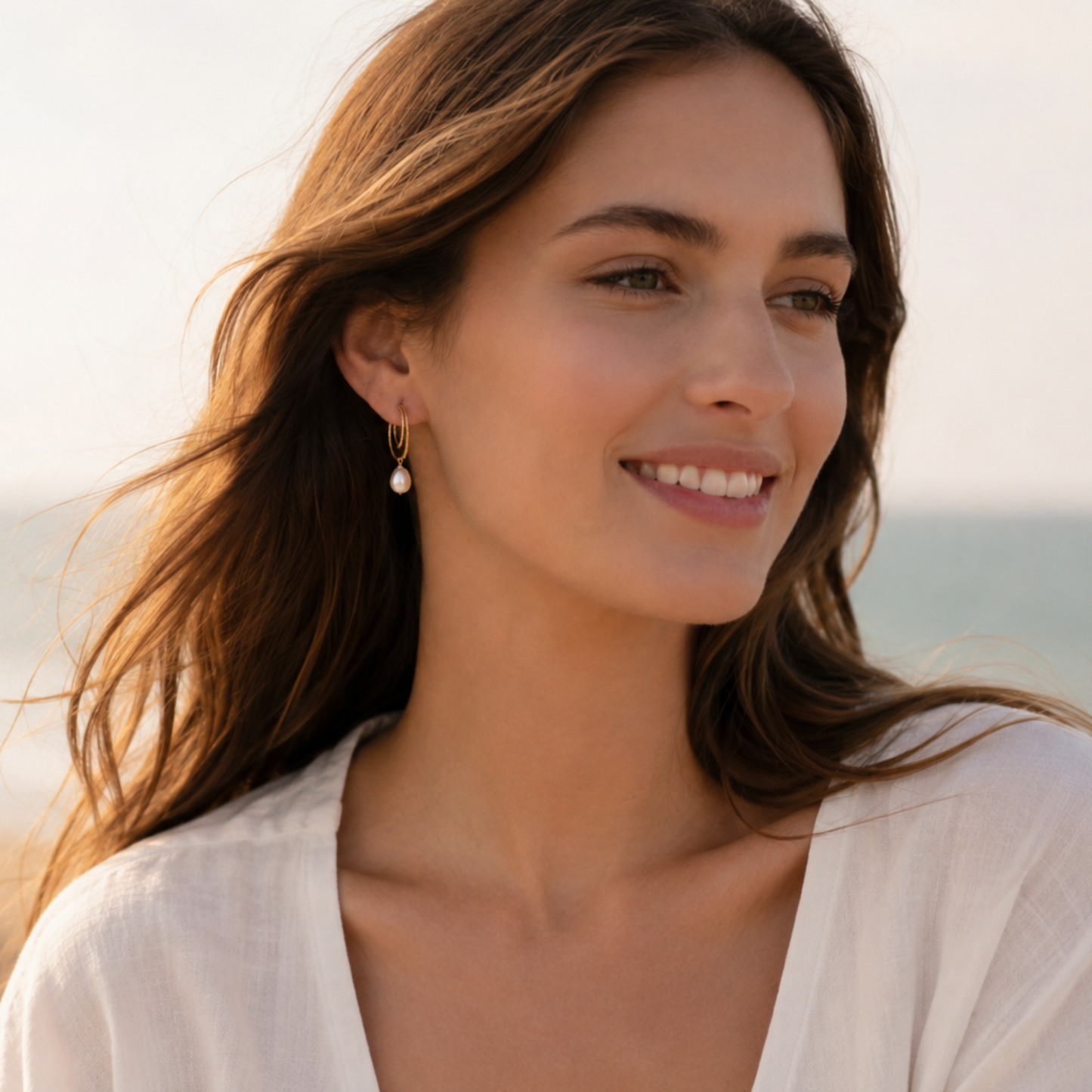 Modelo luciendo pendientes DOUX de plata  de ley bañados en oro 18K con perla cultivada colgante al aire libre