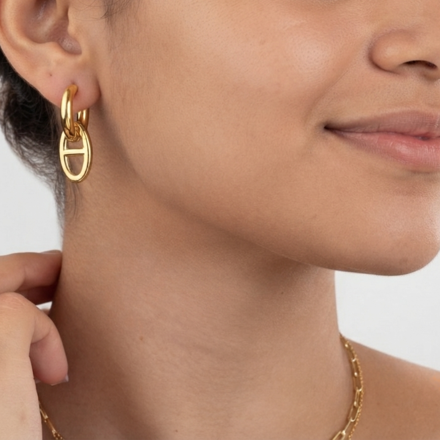 Modelo luciendo pendientes MAGLIA acero waterproof bañado en oro 18K transformables en la oreja 