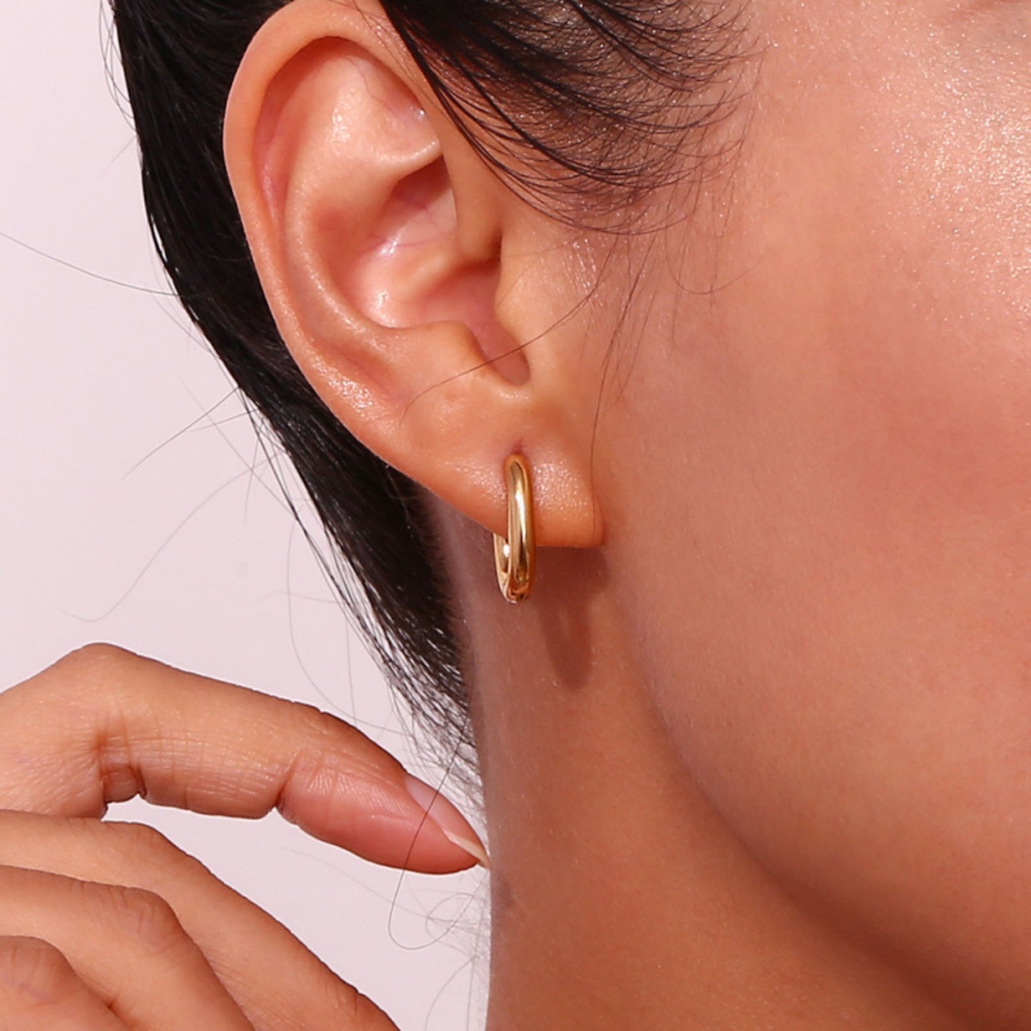 Modelo luciendo pendientes OVALE de aro ovalado dorado de acero waterproof bañado en oro 18K