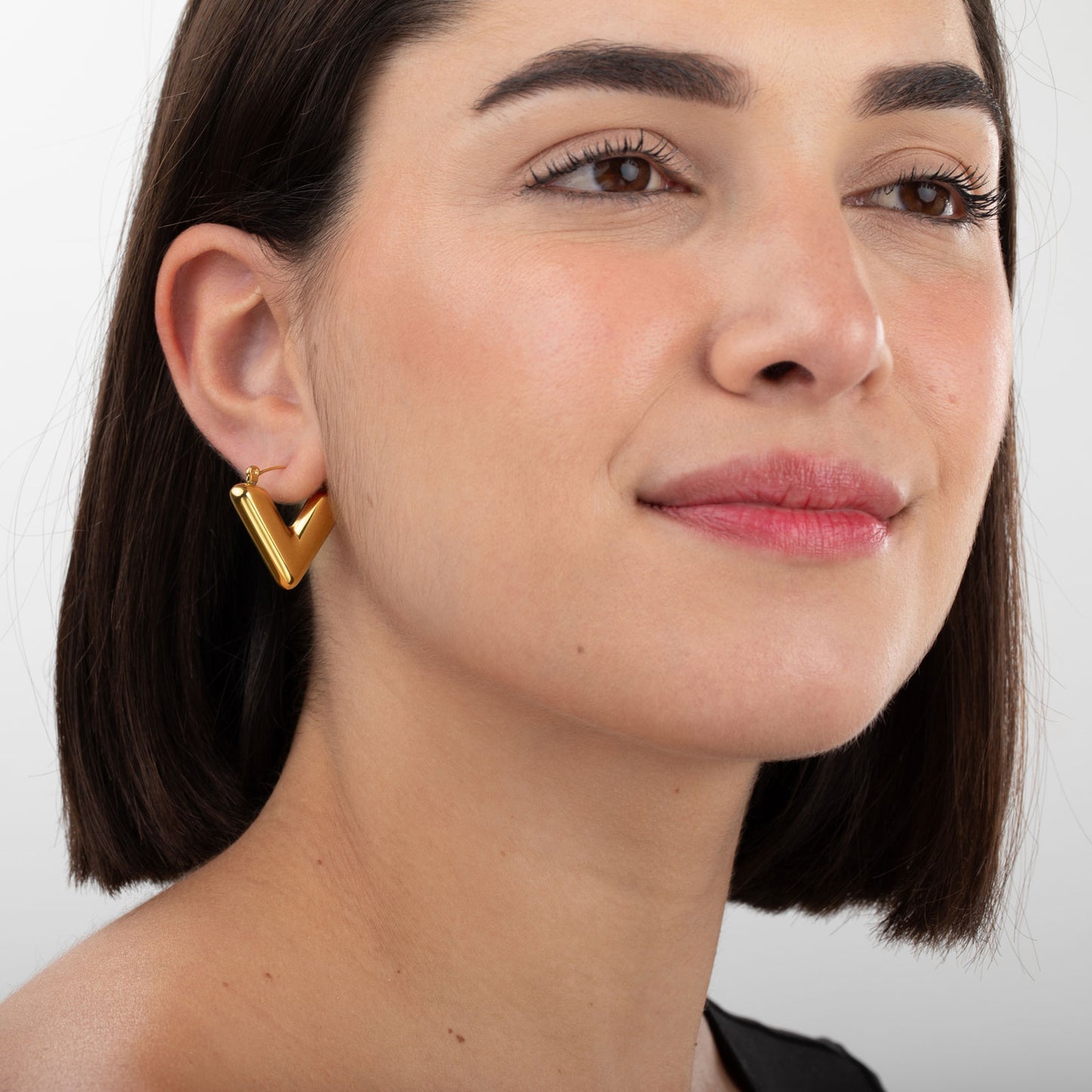 Modelo luciendo pendientes VITTORIA dorados waterproof oro 18k en forma de V